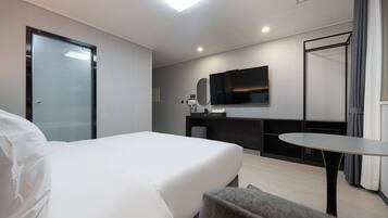 Una habitación de hotel moderna con una cama, un escritorio, un televisor de pantalla plana y una mesita.