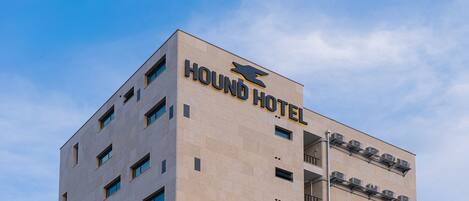 Un edificio con el letrero "HOUND HOTEL" y varias unidades de aire acondicionado en la fachada.