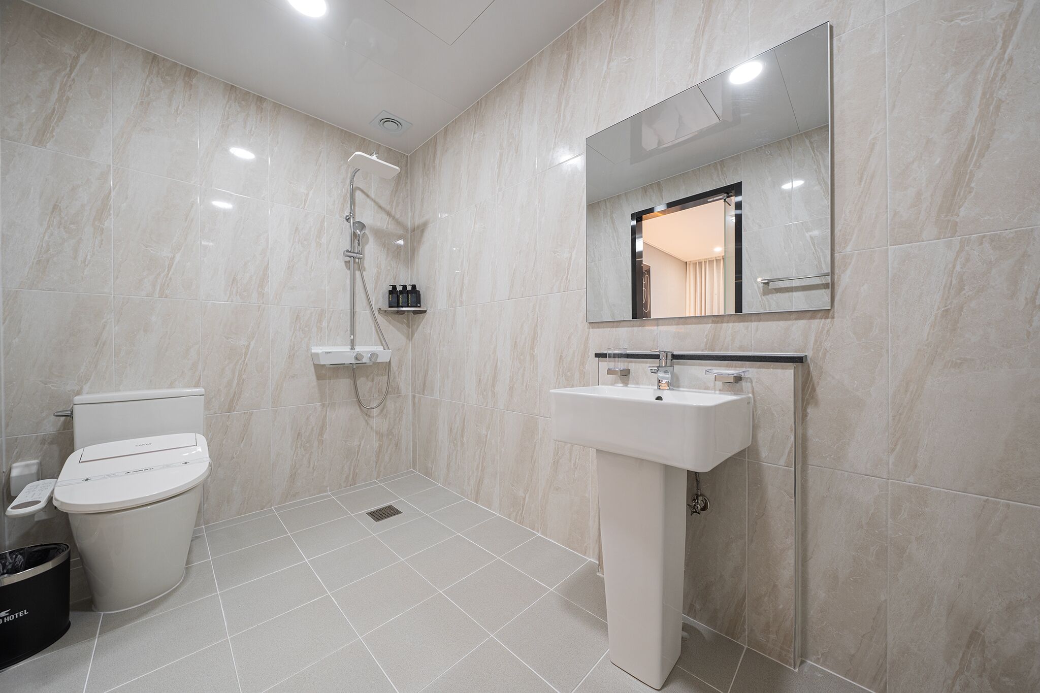 Un baño moderno con inodoro, ducha, lavabo y espejo.