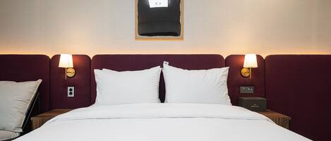 Habitación de hotel con una cama grande, dos mesitas de noche, una lámpara de pared y un cuadro enmarcado sobre la cama.