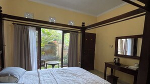 A bedroom with a four-poster bed, a wooden desk, and a small table. - Chic 1-bedroom apartment in charming Bali with WiFi, AC. Hot and cold water (Bali)