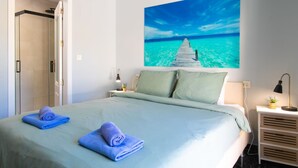 A bedroom with a bed, a nightstand, a lamp, a wall art of a pier, and a door leading to a bathroom. - Bugambilla by Interhome (Almuñécar)