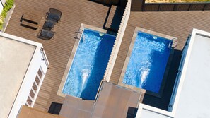 An aerial view of a rooftop with two swimming pools, wooden deck, and outdoor seating. - Buan Cordelia Pool Villa Pension (Buan)