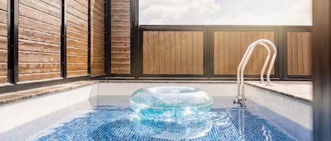A hot tub in a room with wooden walls and a view of the sky.