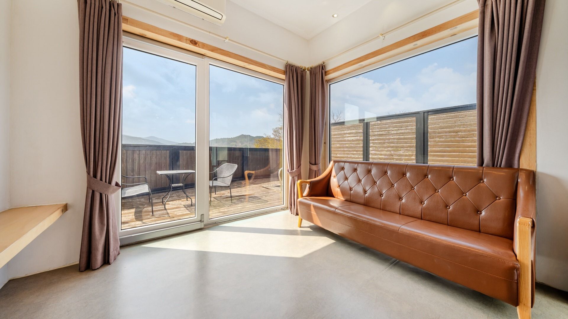 A spacious room with a large sliding glass door leading to an outdoor patio area.