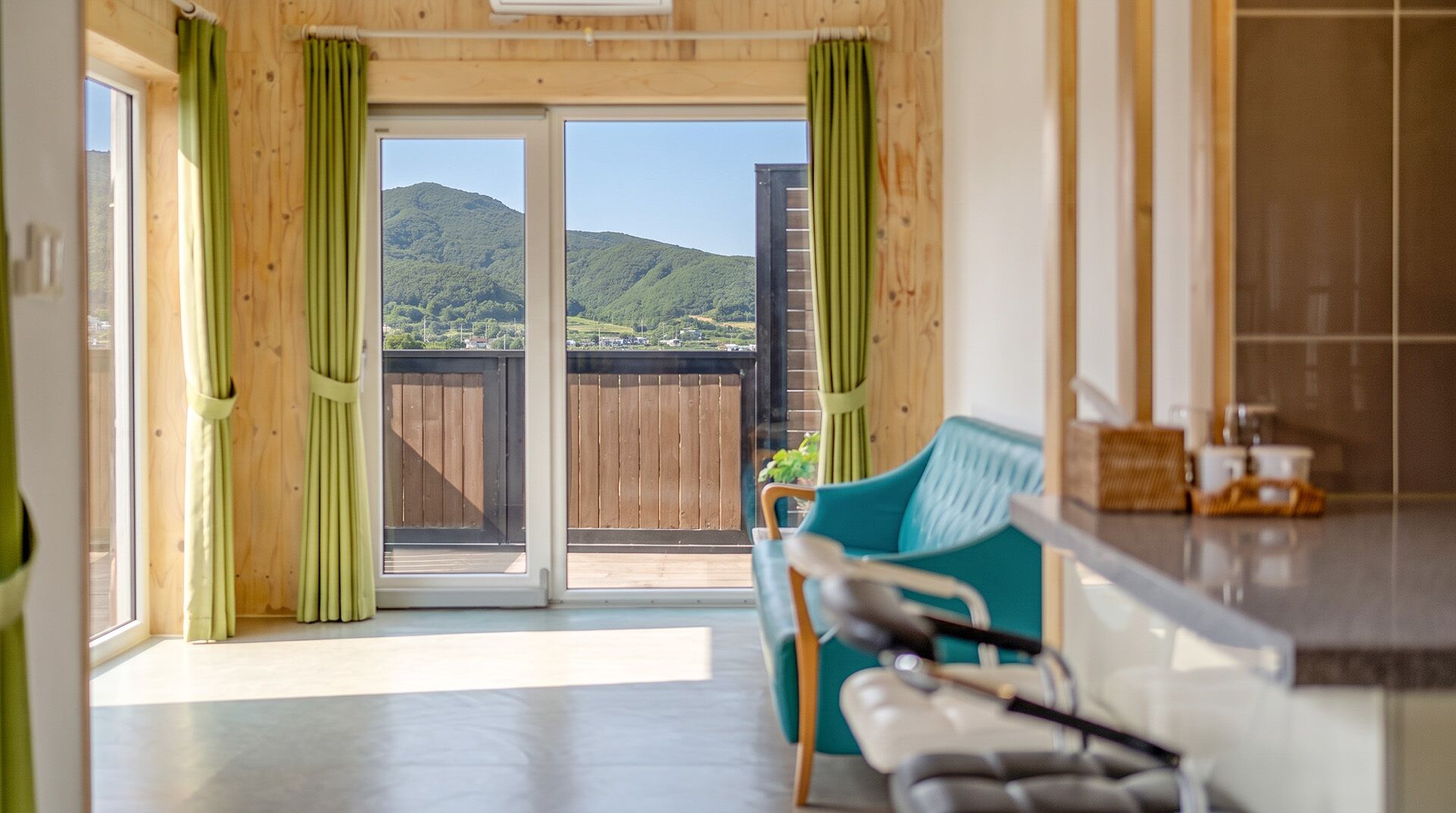A room with a sliding glass door leading to a balcony with a view of a hilly landscape.