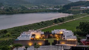 A modern hotel with a rooftop terrace overlooking a river, surrounded by lush greenery. - Buan Cordelia Pool Villa Pension (Buan)