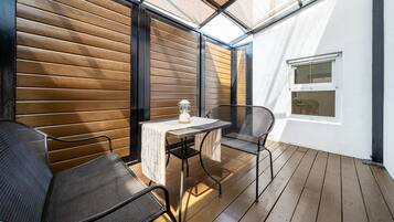 An outdoor patio with a table and chairs, a lantern, and a window.
