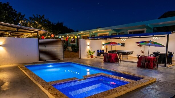 Ein Swimmingpool mit Fliesenbordur, Sitzgelegenheiten im Freien mit Sonnenschirmen und Lichterketten.