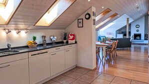 A modern kitchen with a central island, a dining area with a table and chairs, and a living room with a fireplace.