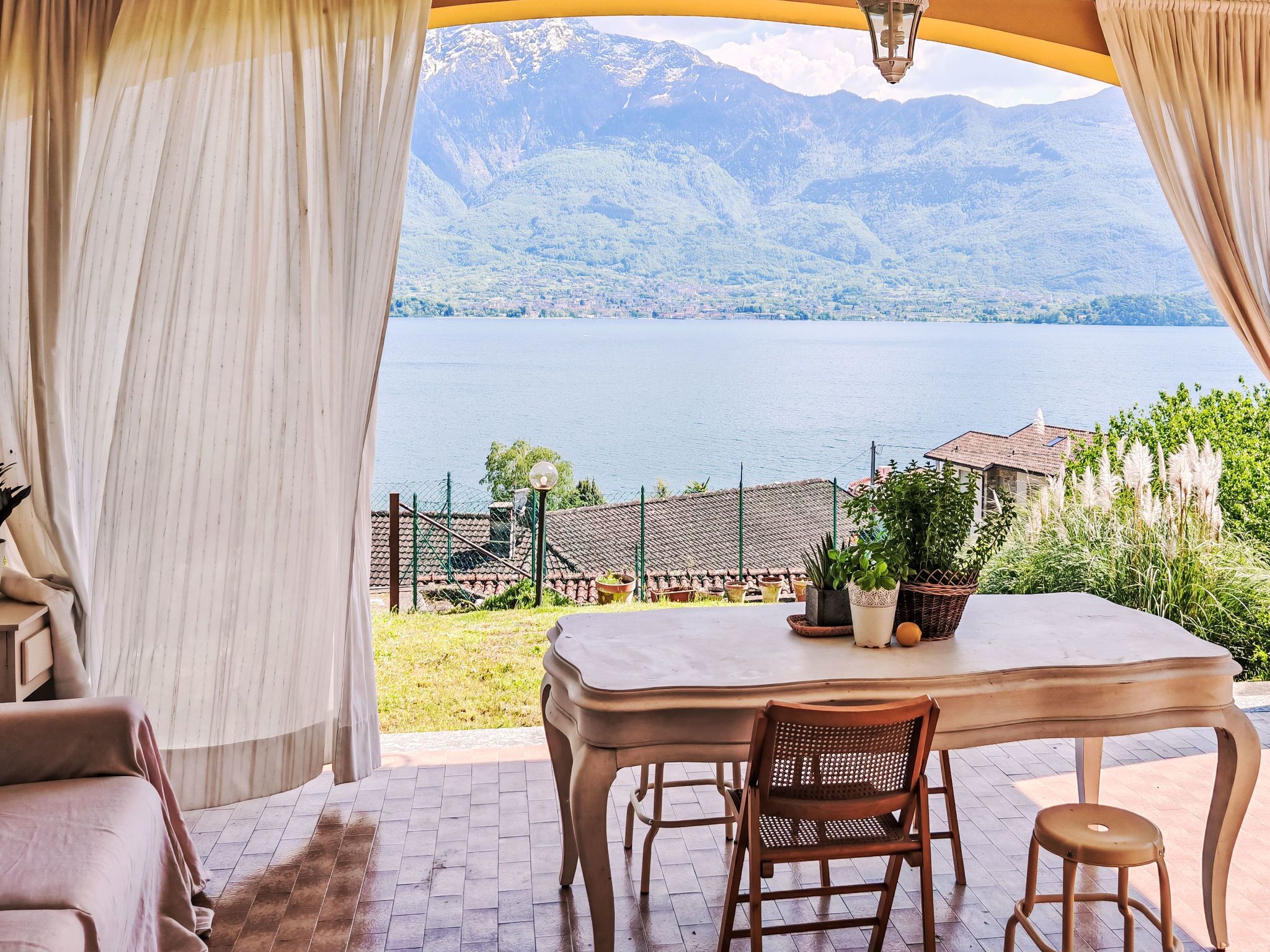 Une terrasse avec une table et des chaises, offrant une vue sur un lac et des montagnes.