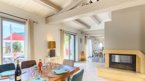 A dining area with a wooden table set for four, a fireplace, and a view of the outdoors.