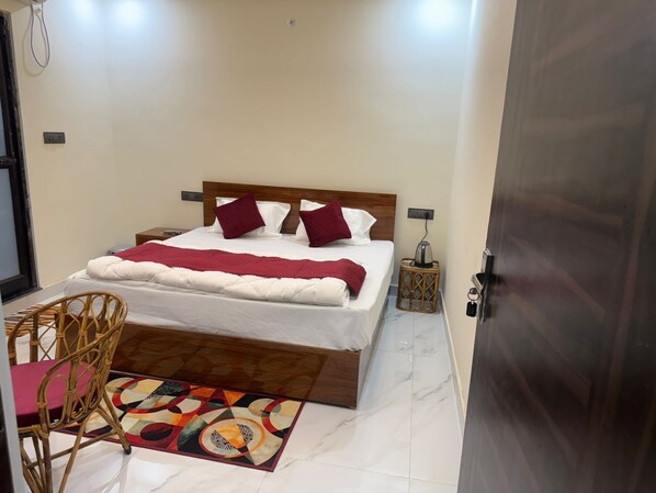 Un dormitorio ordenado con cama, una silla, una mesita y una puerta.