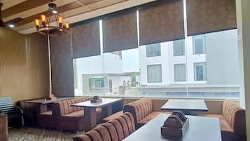 Un restaurante moderno con techos altos, techo con estampado y ventanas amplias que ofrecen vista a edificios.