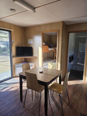 Una habitación compacta con una mesa de madera, sillas, televisor y una cama litera.