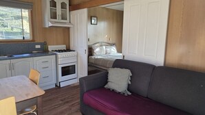 Interior compacto de una caravana con kitchenette, zona de comedor y espacio para dormir.