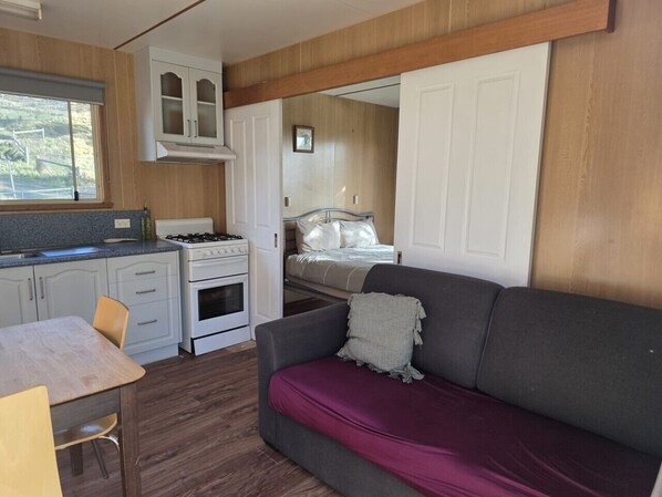 Interior compacto de una caravana con kitchenette, zona de comedor y espacio para dormir.