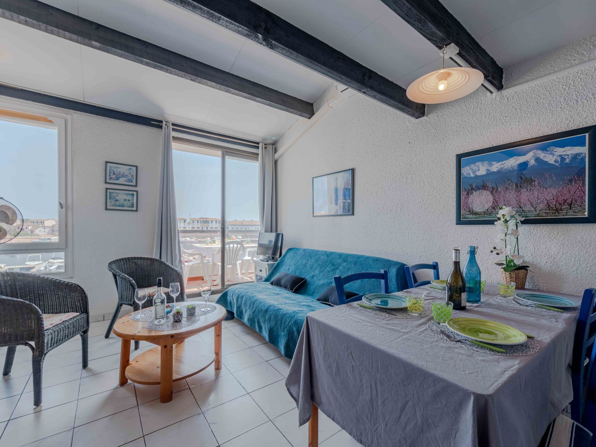 A modern room with a balcony, a dining table set for two, and a sofa.