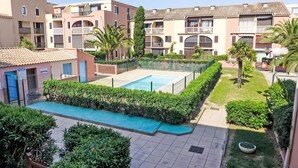 Edificio residencial con piscina rodeada de vegetación y un pequeño jardín.