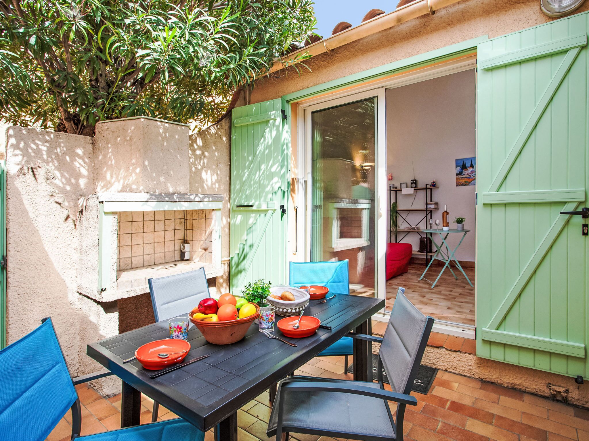 Patio esterno con tavolo apparecchiato per un pasto, una griglia e vista sulla casa.