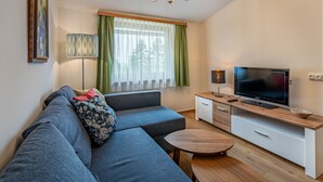 A modern living room with a sectional sofa, a flat-screen TV, a wooden coffee table, and a floor lamp. - Simonhöhe by Interhome (Sankt Urban)