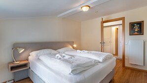 A neatly made bed with white linens and towels, a bedside lamp, and a small bedside table. - Simonhöhe by Interhome (Sankt Urban)