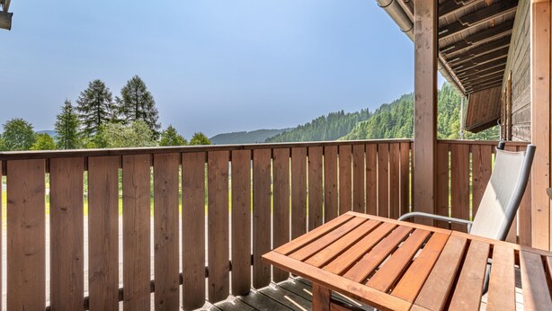 A wooden deck with a table and chairs, overlooking a forested landscape. - Simonhöhe by Interhome (Sankt Urban)