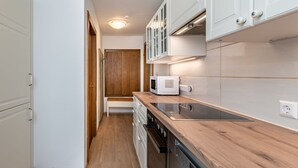 Une cuisine de taille réduite avec des meubles blancs, un four à micro-ondes, une cuisinière et un lave-vaisselle.