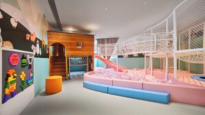 A children's play area with a slide, soft play surfaces, and a wall with colorful character decorations. - Q-Box Hotel Hangzhou Bay Ningbo (Ningbo)