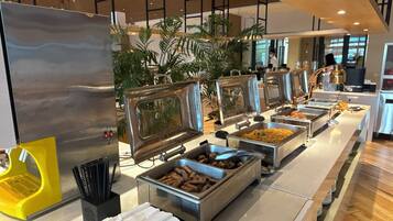 A buffet setup with various food stations, including a grill, a salad bar, and a meat station.