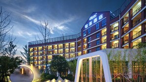 A hotel with multiple floors, outdoor lighting, and a landscaped area with a swing set. - Q-Box Hotel Hangzhou Bay Ningbo (Ningbo)