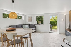 Un espacio habitable moderno con zona de comedor, sofá y ventanas amplias.