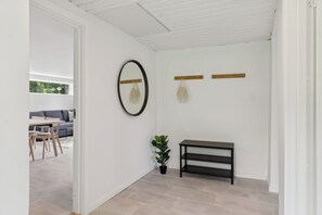 A hallway with a bench, a potted plant, a mirror, and a shelf with bags. - Lovely cottage, close to beach and forest (Nakskov)
