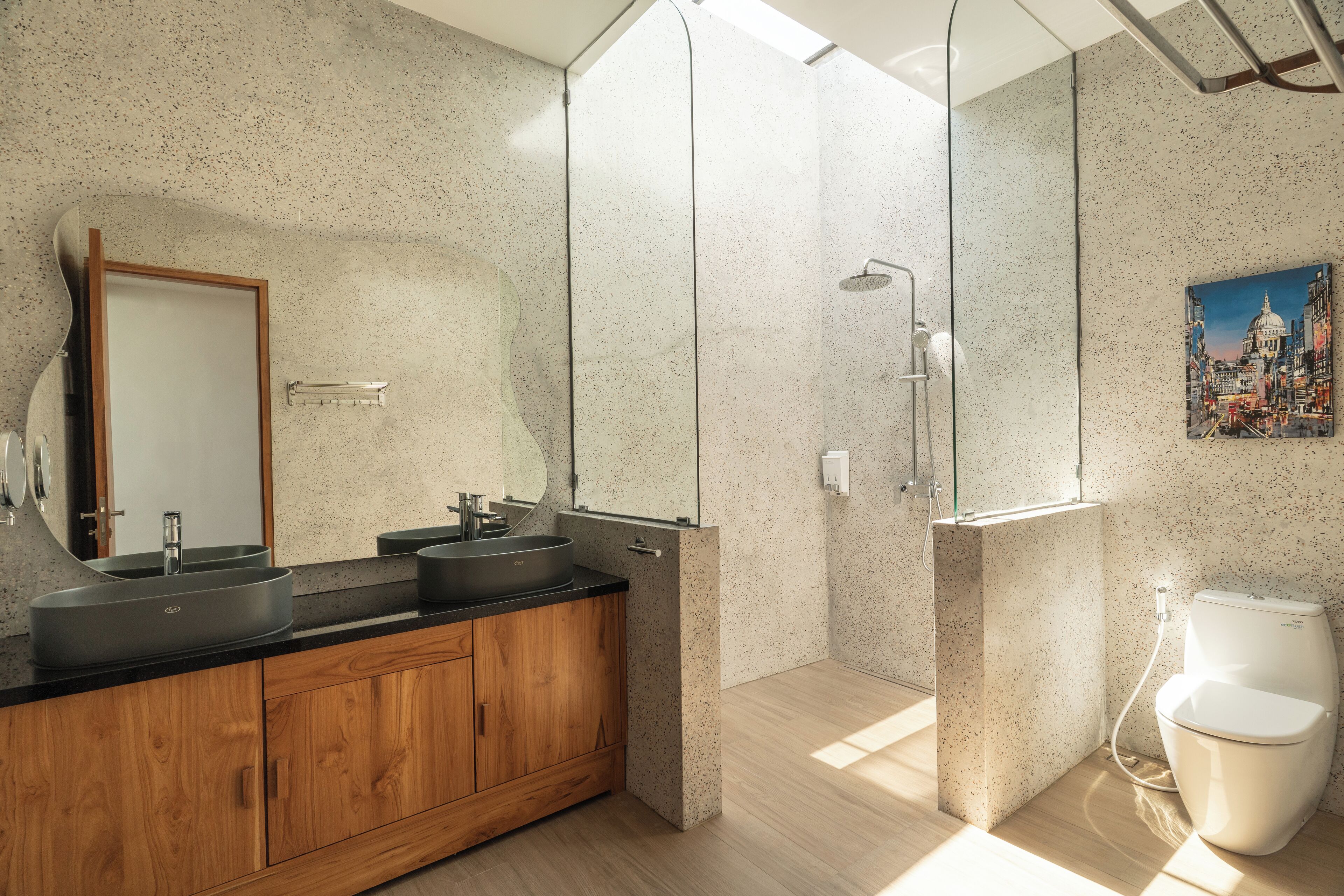 Un baño moderno con un lavamanos independiente, cabina de ducha con mampara de vidrio y un inodoro.