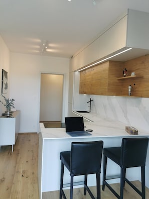 Eine moderne Küche mit Marmorarbeitsplatte, zwei schwarzen Stühlen und einem Laptop.