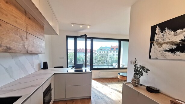 A modern kitchen with a large window, wooden cabinets, and a minimalist design. - free Parking, center location, Nuslesky Pivovar sunset balcony home (Hlavní město Praha)