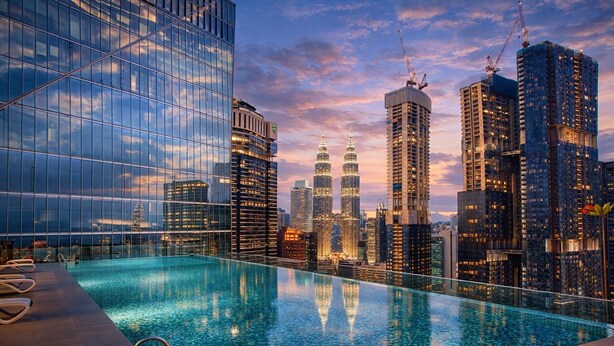 Ein Infinity-Pool auf dem Dach mit Blick auf eine Stadtlandschaft, darunter moderne Wolkenkratzer und die Petronas Towers.