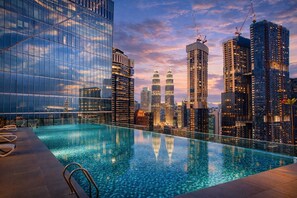 Ein Infinity-Pool auf dem Dach mit Blick auf eine Stadtlandschaft, darunter moderne Wolkenkratzer und die Petronas Towers.