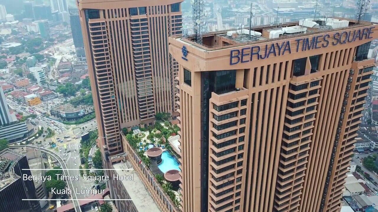 Een hoog hotel met een zwembad op het dak en uitzicht op Kuala Lumpur.