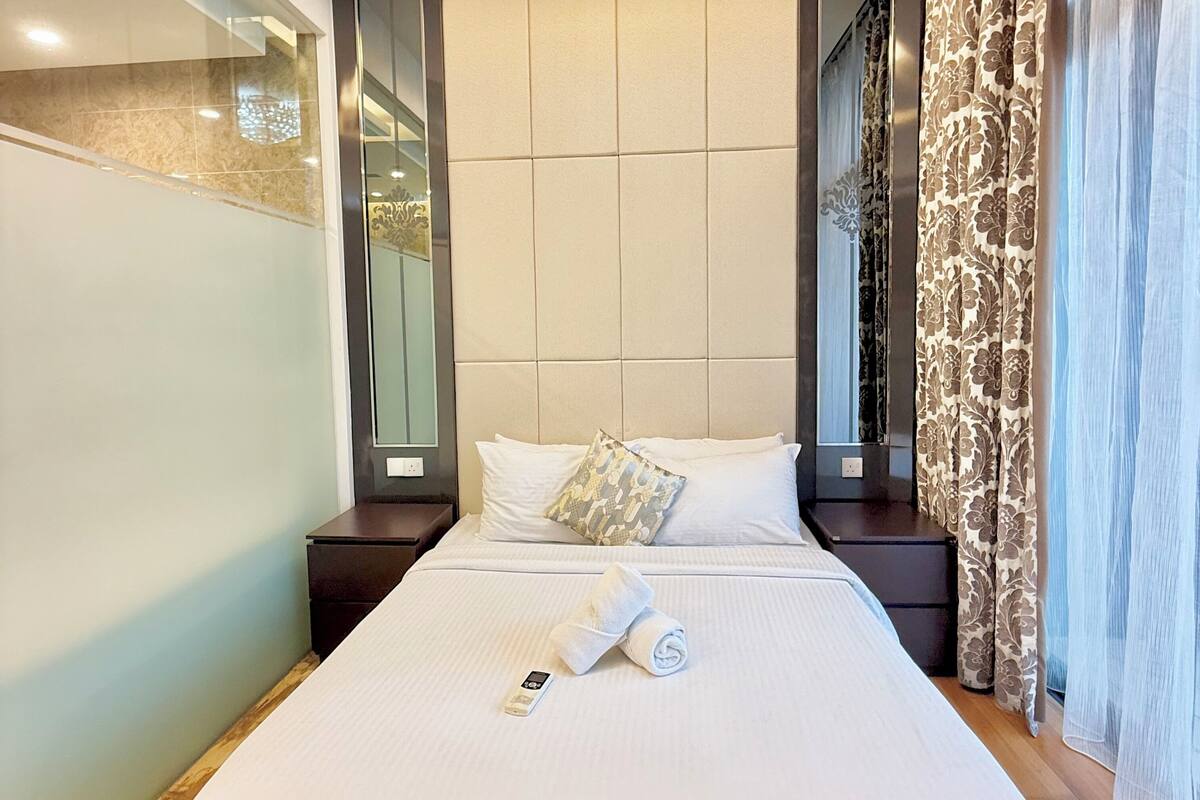 Ein Hotelzimmer mit einem großen Bett, einem Nachttisch, einem Spiegel und einer Deckenleuchte.