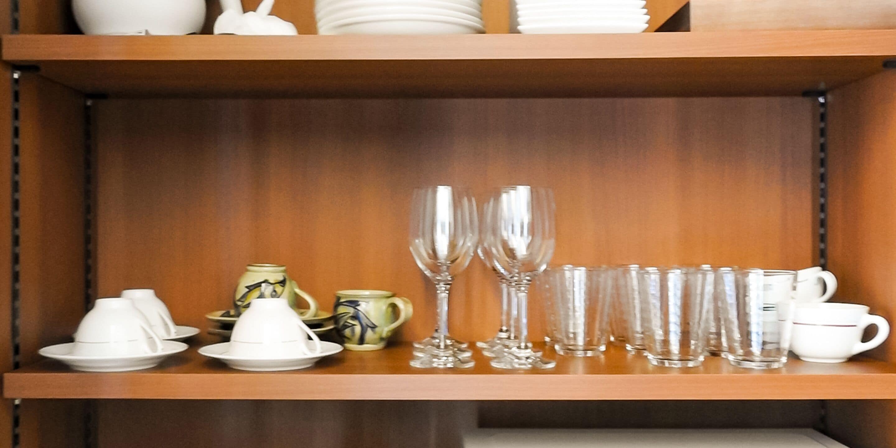 A shelf with various glassware and ceramic items.