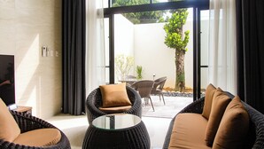 A modern living room with wicker furniture, a glass coffee table, and a view of an outdoor patio area. - villa LIFE INDAH sumuide (Nago)