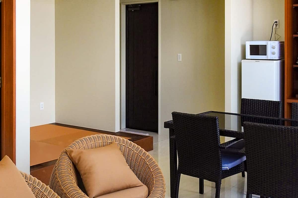 A room with a dining table and chairs, a microwave, and a refrigerator.