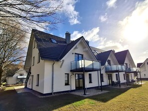 A modern two-story house with a balcony, a garage, and a well-maintained lawn. - Beachfront apartment with balcony, pool, and sauna - Rex Rugia - Rex Rugia (Göhren)