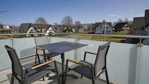 A balcony with a table and chairs, overlooking a residential area with houses and a clear sky. - Beachfront vacation rental with a balcony, access to the pool and sauna - Rex Rugia H-1010 - (Göhren)