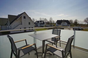A balcony with a table and chairs, overlooking a residential area with houses and a clear sky. - Beachfront vacation rental with a balcony, access to the pool and sauna - Rex Rugia - Rex Rugia (Göhren)