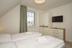 A bedroom with two beds, a TV, and a wardrobe. - Beachfront vacation rental with a balcony, pool access, and a sauna - Rex Rugia - Rex Rugia (Göhren)