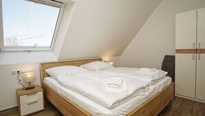 A neatly made bed in a room with a sloped ceiling, a single bedside table with a lamp, and a wardrobe. - Beachfront vacation rental with a balcony, access to the pool and sauna - Rex Rugia - Rex Rugia (Göhren)