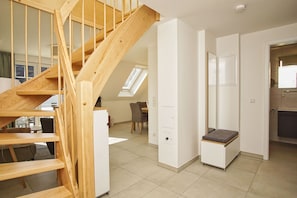 A modern apartment with a wooden staircase, a dining area, a kitchen, and a living space with a skylight. - Beachfront vacation rental with a balcony, access to the pool and sauna - Rex Rugia H-1010 - (Göhren)
