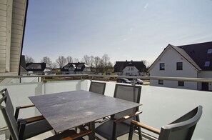 Ein Balkon mit Tisch und Stühlen mit Blick auf eine Wohngegend mit Häusern und parkenden Autos.